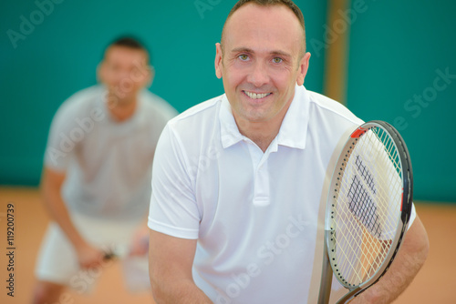Two smiling men playing tennis