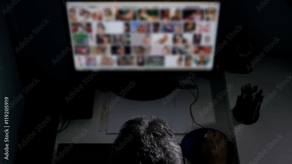 man watches surfing pornography site on pc looking for virtual sex at night in a dark room,screen is out of focus uhd 4k,useful to represent internet easy porn accessibility and social issue