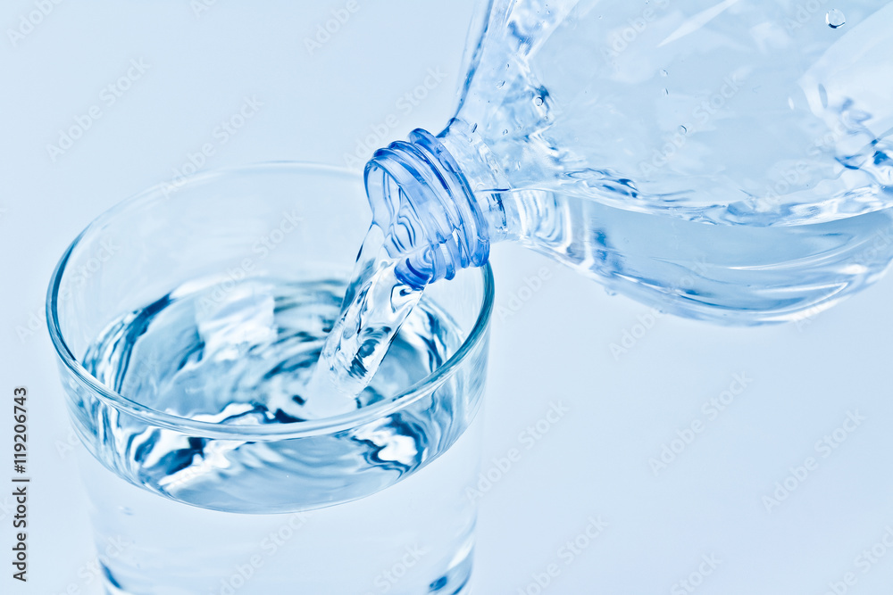 filling a glass with water through bottle, nutrition and health-care concept filling a glass with water through bottle, nutrition and health-care concept