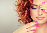 Beautiful model girl with curly red hair . Magenta color manicure on nails . 