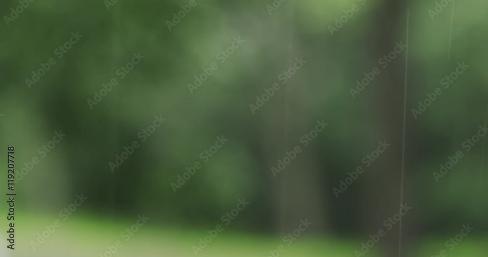 rain falling in fron of defocused green town background