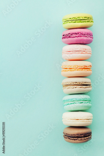 Cake macaron or macaroon on blue background from above. Colorful almond biscuits. Vintage card. Flat lay.