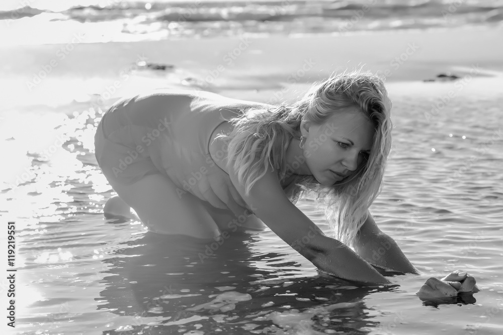 Fototapeta premium Young, beautiful woman posing at the seaside in summer. Black and white photography.