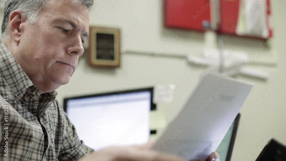 A foreman in an industrial looking office reviews paperwork A foreman in an industrial looking office reviews paperwork