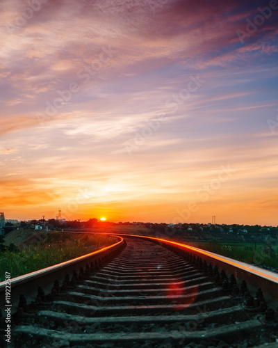 sunset over railroad in violet sky with clouds