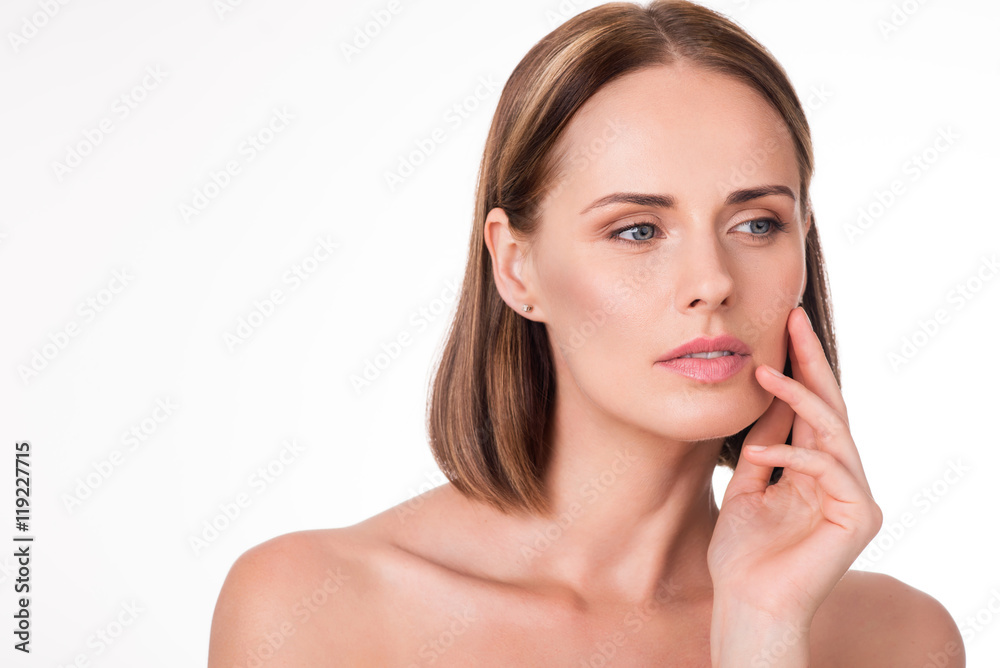 Wistful young woman applying cosmetics