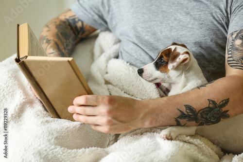 Man with cute dog reading book