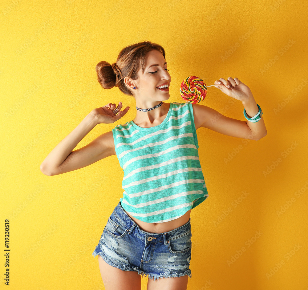 Beautiful girl with candy on yellow background Beautiful girl with candy on yellow background