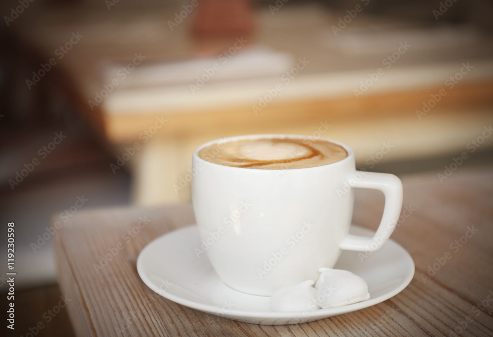 Cup of coffee with meringues on wooden table