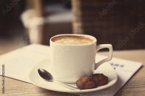 Cup of fresh coffee and morning newspaper on wooden table