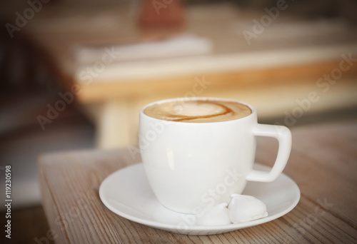 Cup of coffee with meringues on wooden table