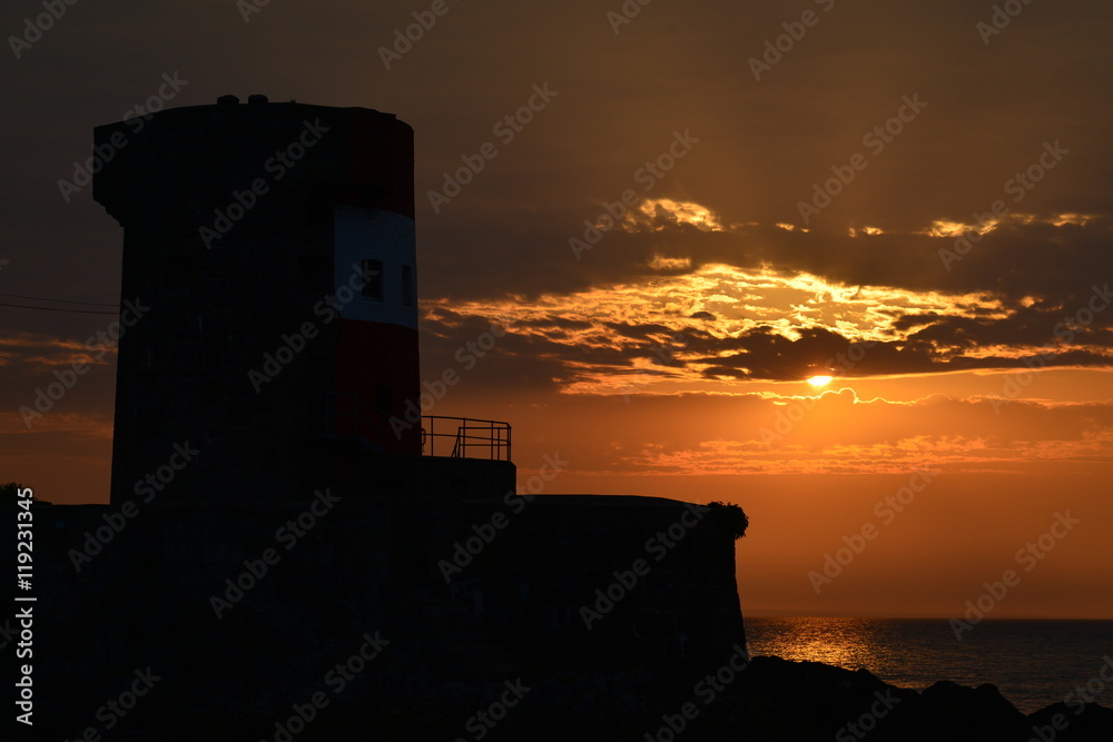 Archirondel tower, Jersey, U.K. Telephoto image of a dramatic Summer sunrise with a 19th century tower in silhouette. Archirondel tower, Jersey, U.K. Telephoto image of a dramatic Summer sunrise with a 19th century tower in silhouette.