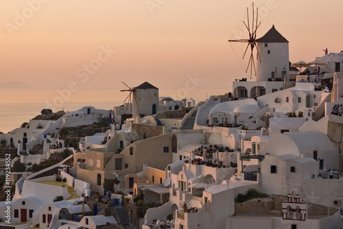 Sunset panorama over white windmills in town of Oia and panorama to Santorini island, Thira, Cyclades, Greece