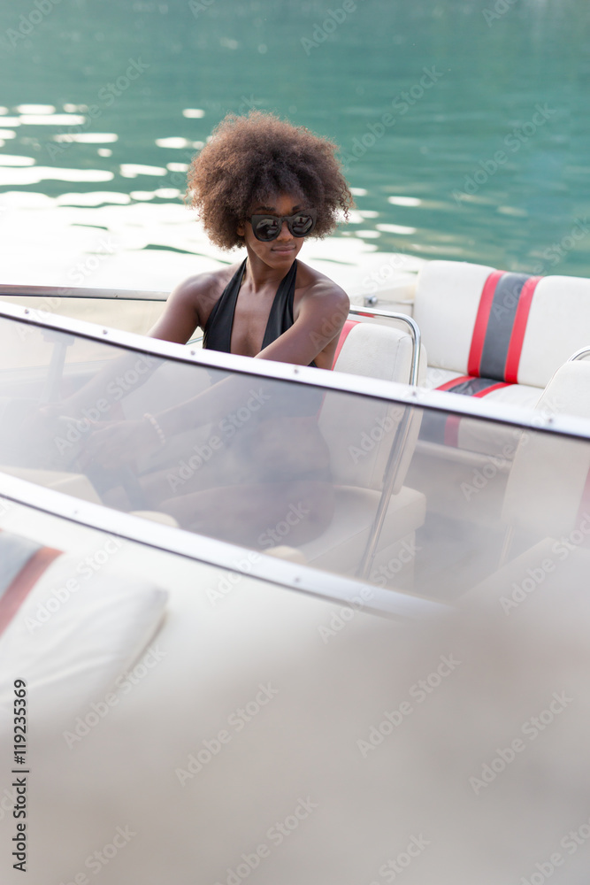Obraz premium Sexy afro american woman with sunglasses posing on her own yacht