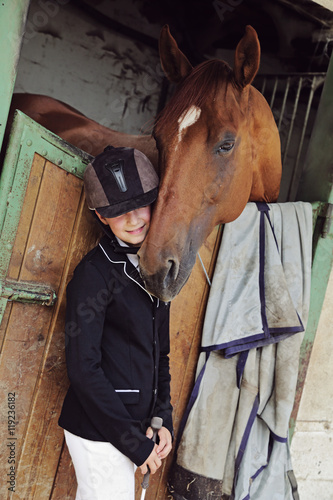 Fototapeta Naklejka Na Ścianę i Meble -  jeune fille 11 ans en tenue d'équitation dans écurie, box avec cheval 