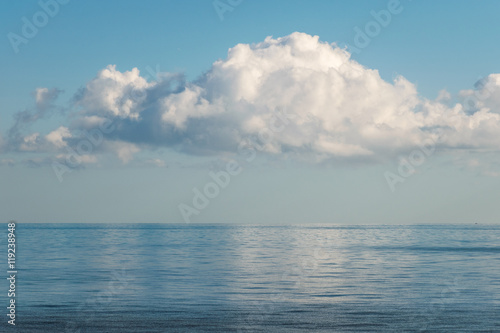 white cloud reflected in calm, still sea on a blue summer's day