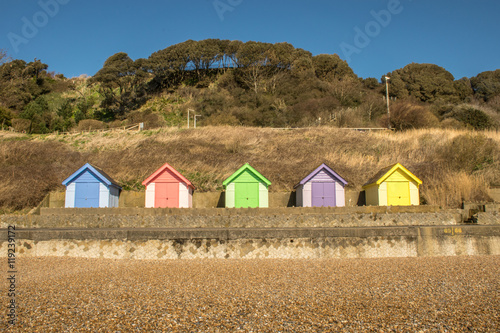 Bright and colourful wooden beach huts on coastal promenade between Folkestone and Sandgate in Kent