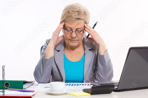 Elderly business woman analyzing financial charts at desk in office, business concept
