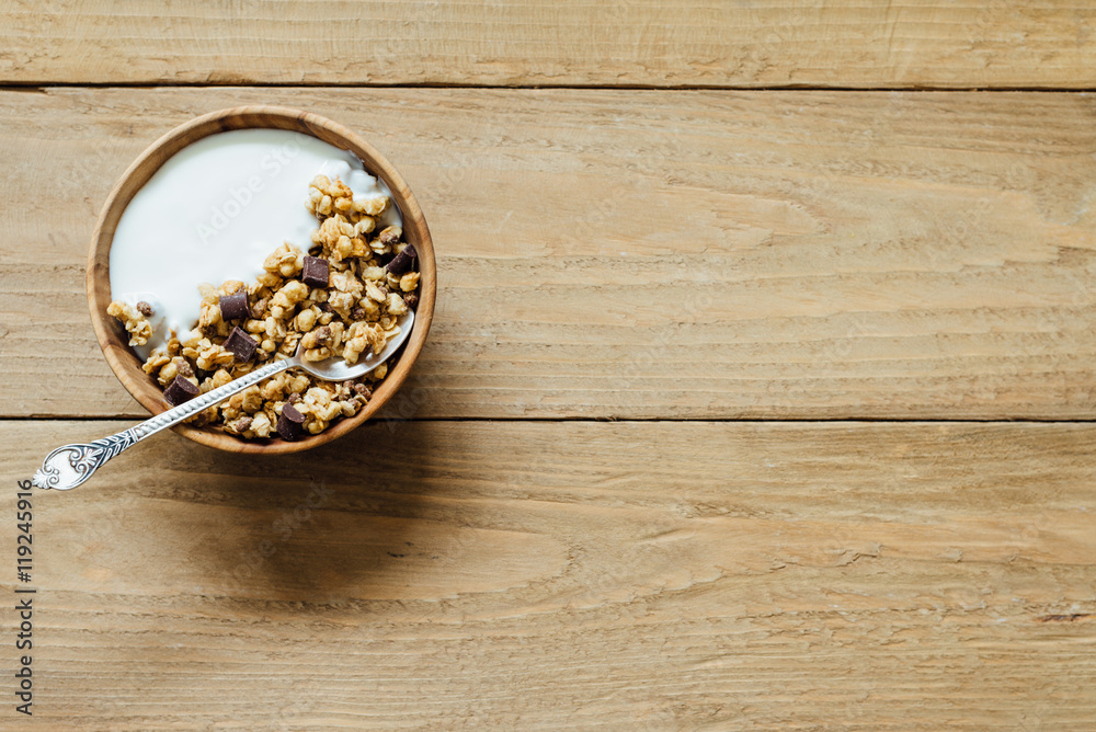 Homemade oatmeal chocolate granola with yogurt in wooden bowl Homemade oatmeal chocolate granola with yogurt in wooden bowl