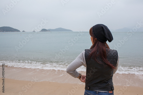 Hong Kong tourist woman at Repulse Bay beach. Beautiful Asian woman in leather jacket and warm sweater enjoying view. Hong Kong travel and tourism concept.