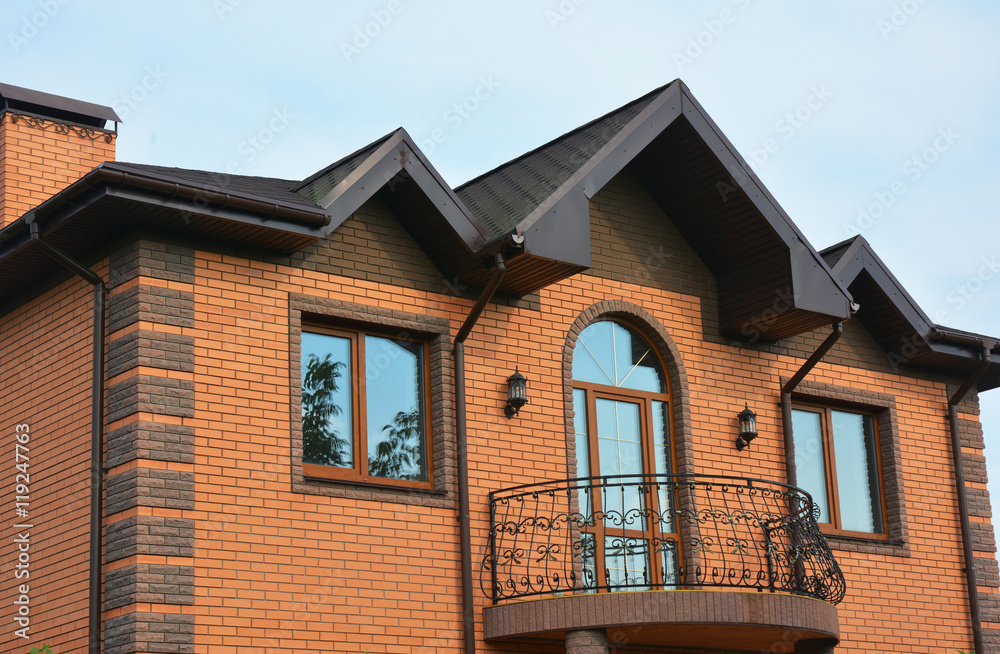 Building brick house construction with different types of roof design and metal balcony