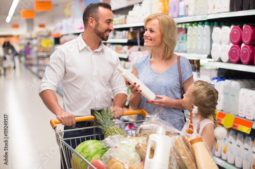 Family selecting shampoo in supermarket.