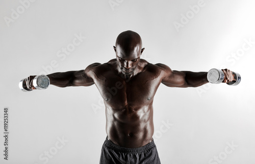 African man doing arms exercise with dumbbells