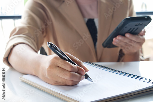 Business girl Hand write note and holding smartphone.