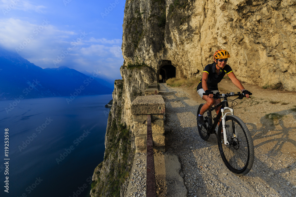 Mountain biking on Sentiero della Ponale, Riva del Garda, Italy. Amazing view of Lake Garda in background.