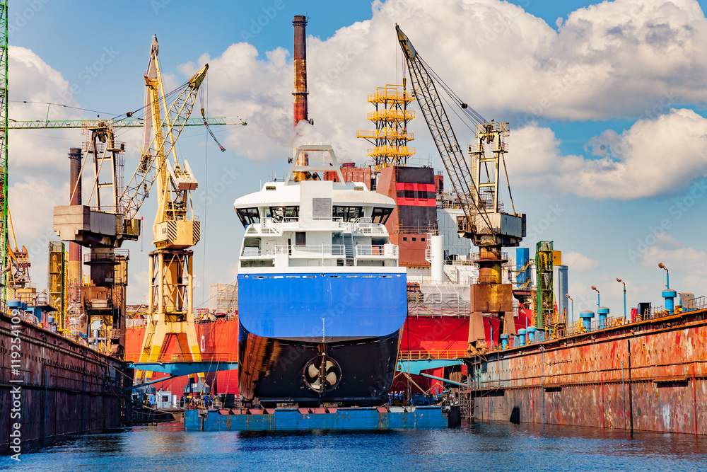 Big ship under repairing on floating dry dock in shipyard.
