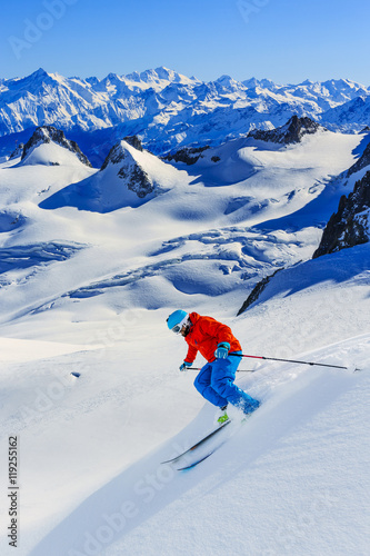 Fototapeta Male skier skiing in fresh snow off ski slope on a sunny winter day at high mountain in French Alps. Freeski in powder snow.