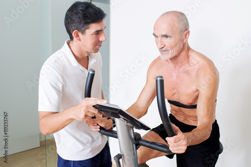Elderly senior with coach on indoor bike