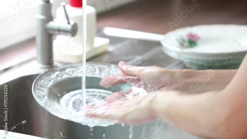 Asian Woman Hand Washing Dishes In A Sink