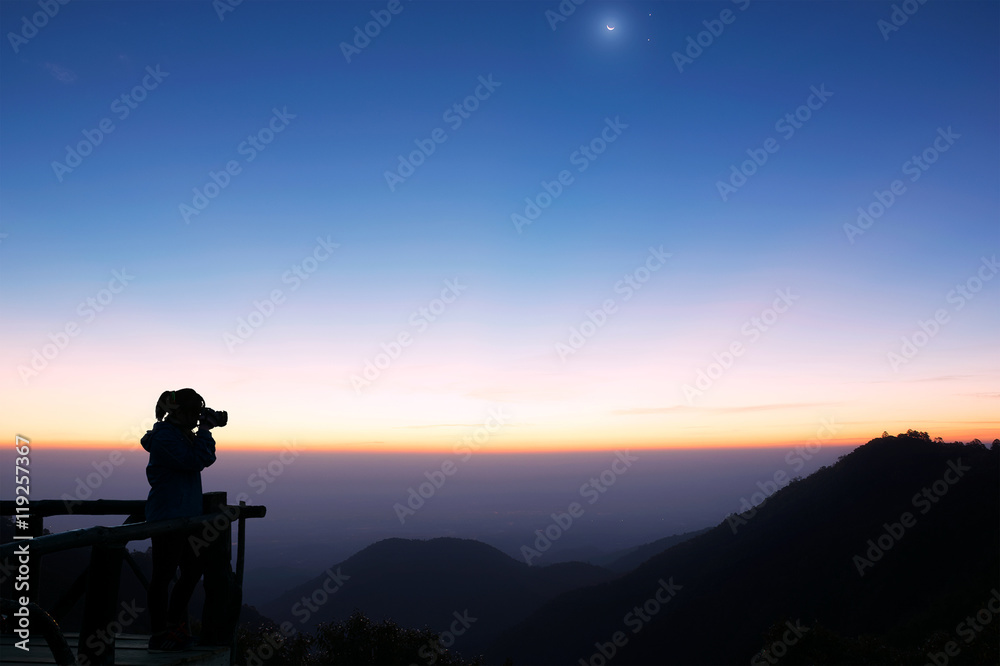 Mountain in the dark and people are shooting at the sun rising from the horizon, the moon and the stars to disappear.(Do not focus on the clarity of the image).
