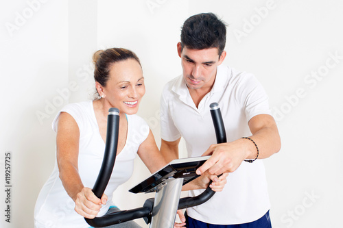 elderly woman during spinning exercise with personal trainer
