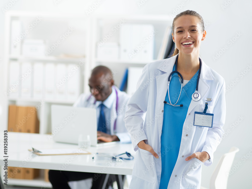A smiling female doctor with a folder in uniform indoors A smiling female doctor with a folder in uniform indoors