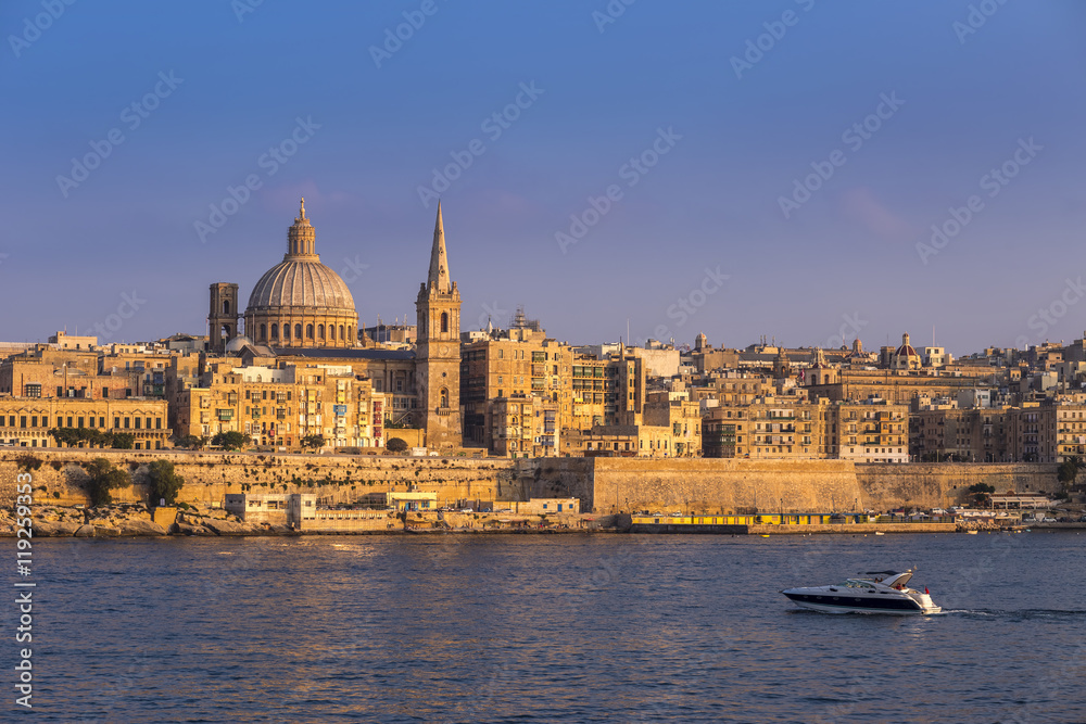 Valletta, Malta - Motorboat and the famous St.Paul's Cathedral with the ancient city of Valletta at sunset