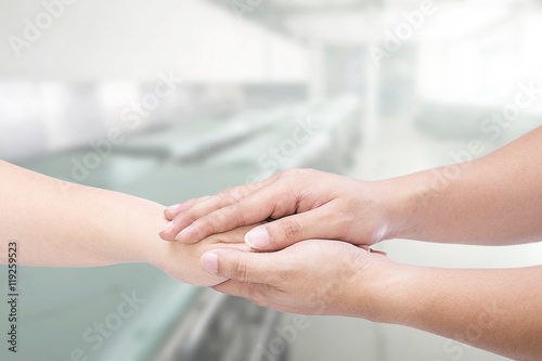 Hand of medical doctor carefully holding patient's hands.