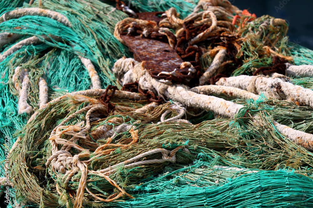 Old ropes and fishing nets and rusty anchors on the shore. Selective focus.