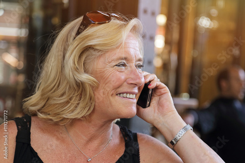 jolie femme blonde senior téléphonant sur une terrasse en été photo