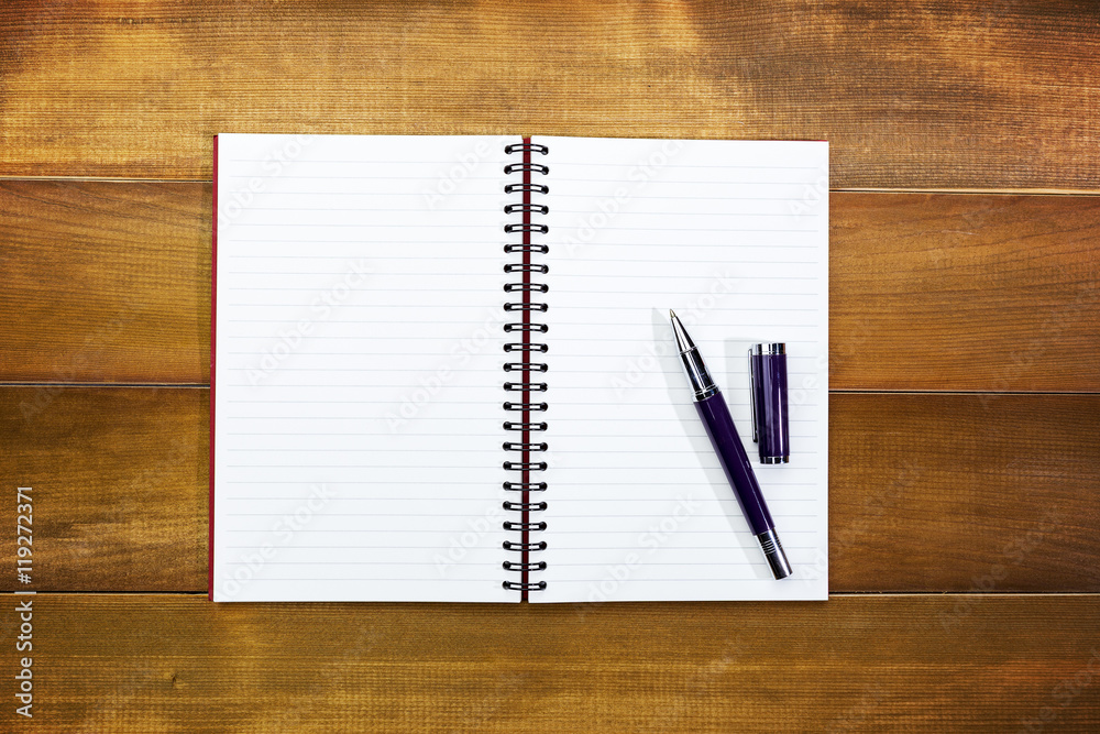 Open notebook with blank pages and pen and glasses on wood office table background with copy space.