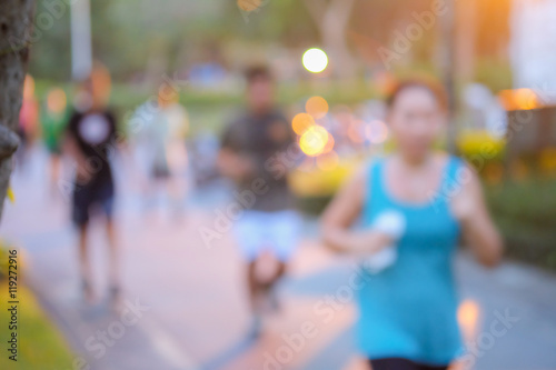 blurred background of people running in the park with sun light