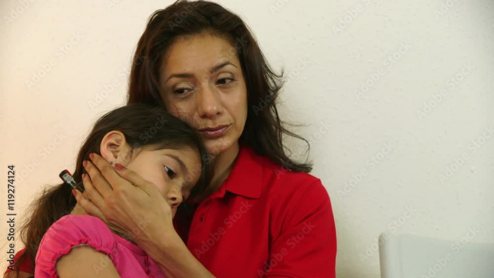 A worried Hispanic single mom with little daughter waits in clinic waiting room for doctor to see her sick child. A worried Hispanic single mom with little daughter waits in clinic waiting room for doctor to see her sick child.