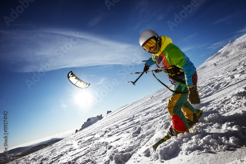 Happy snowboarder with snowkite stands in snowdrift