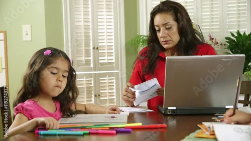 A single mom worries about how to pay bills while children color peacefully unaware of the stress she is feeling. photo