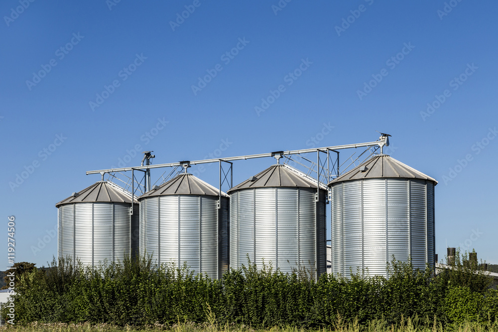 four silver silos in field under blue sky four silver silos in field under blue sky