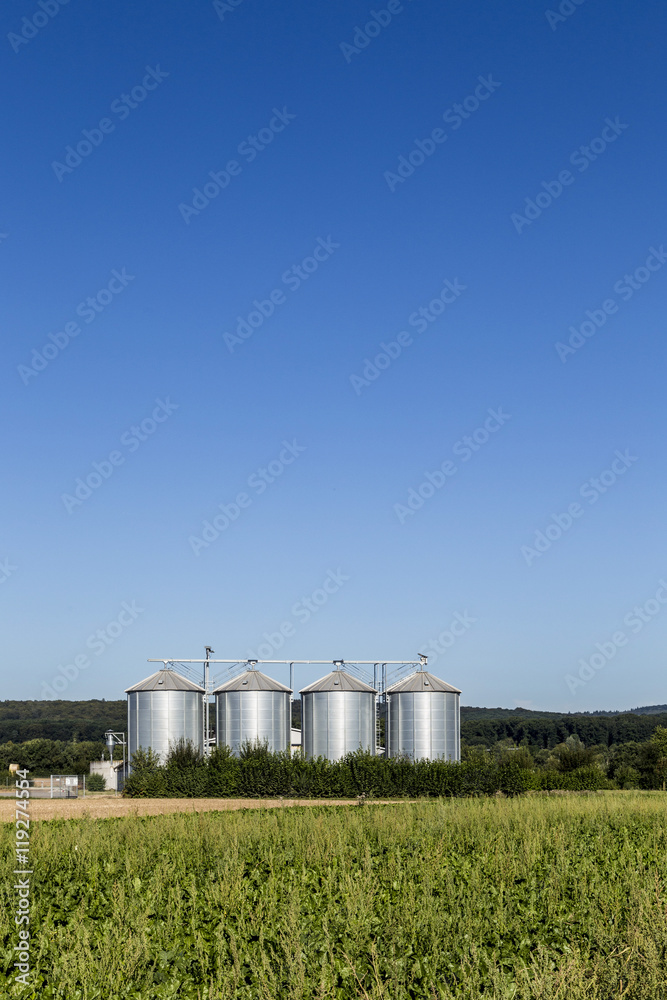 four silver silos in field under blue sky four silver silos in field under blue sky