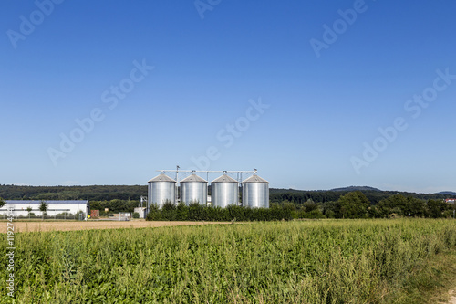 four silver silos in field under   blue sky © travelview
