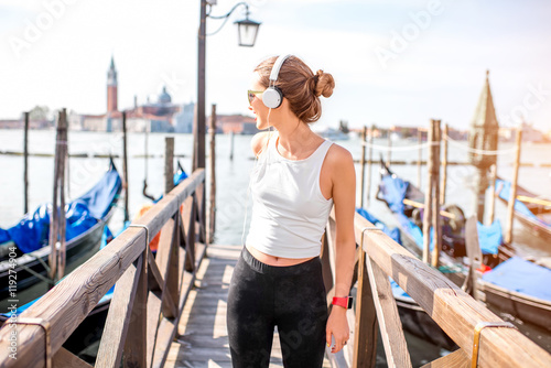 Young woman in sportswear enjoying great view standing on the pier in Venice. Morning exercise in the old town of Venice