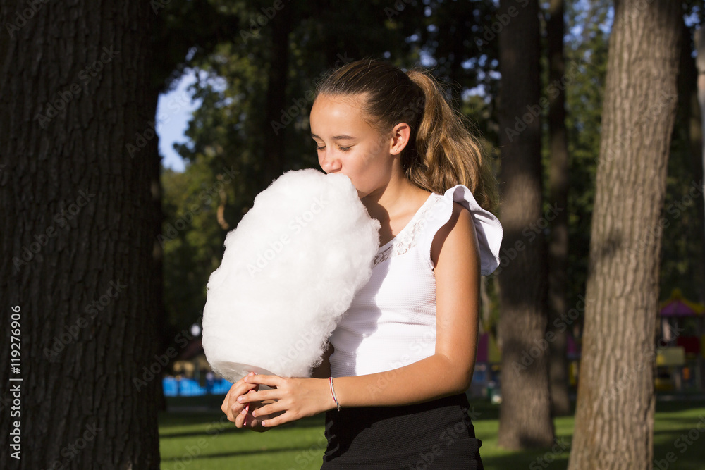 Girl eating cotton candy in a summer park Girl eating cotton candy in a summer park